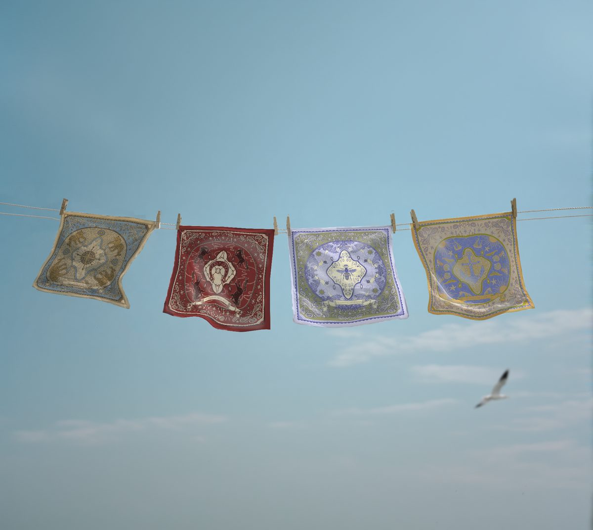 Les quatre foulards Le Noué étendus sur une corde à linge, sous un ciel bleu