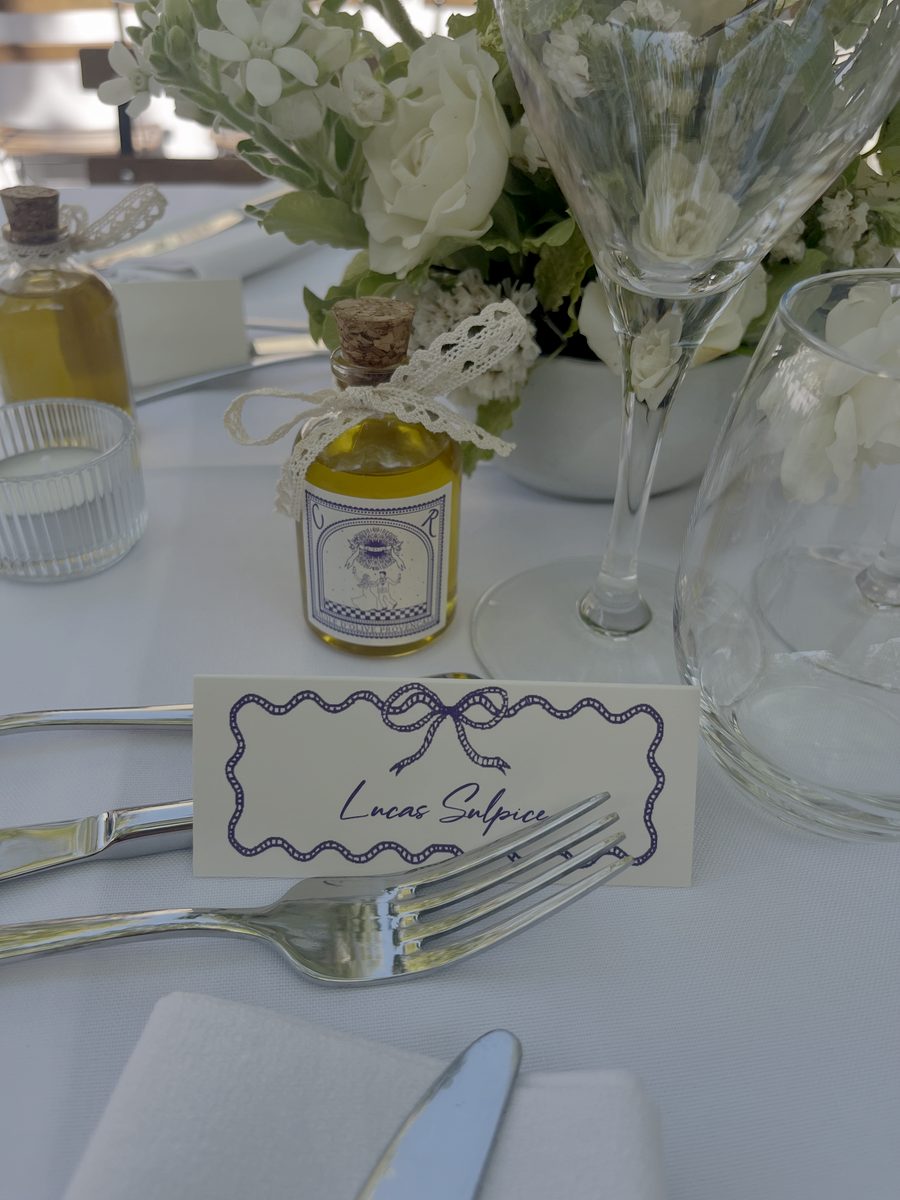 Marque-place calligraphié au nœud bleu, sur une table de mariage dressée en blanc