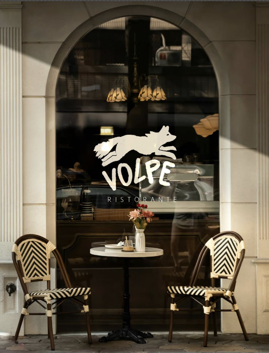 Vitrine du restaurant Volpe : logo renard et mot Ristorante en autocollant écru sur la vitre, terrasse avec deux chaises de bistrot